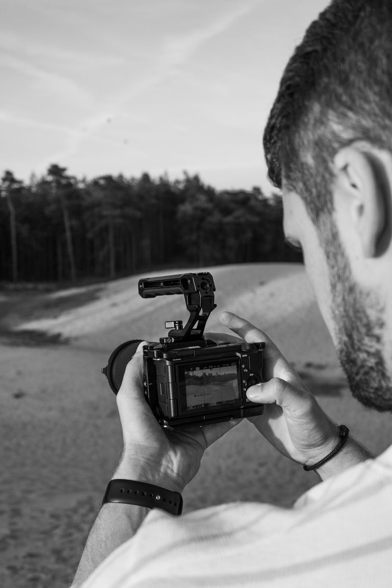 Een arm en hand die een beugel van de camera vasthoudt afgebeeld in zwart wit.