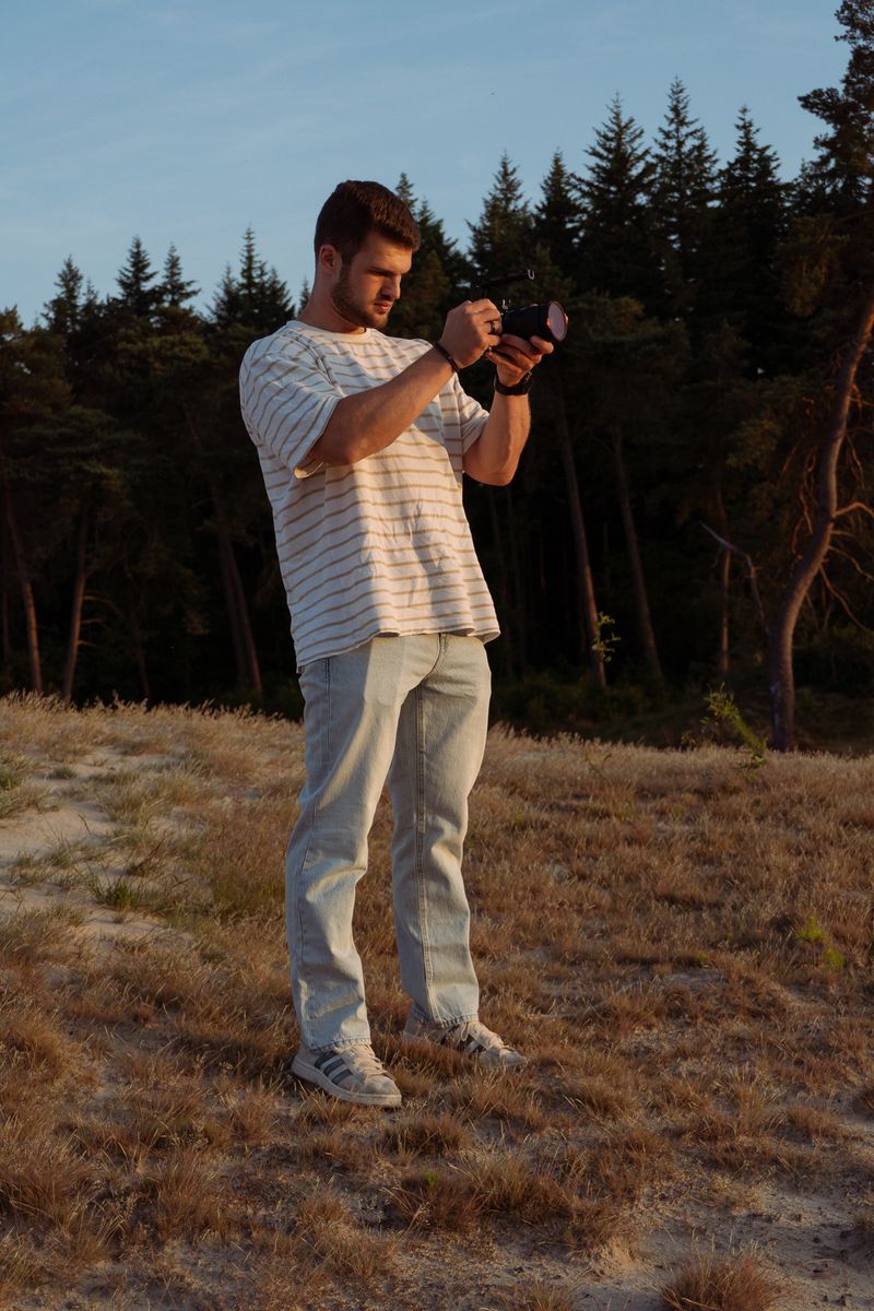 Persoon richt met zijn camera direct naar voren, staand in een open veld