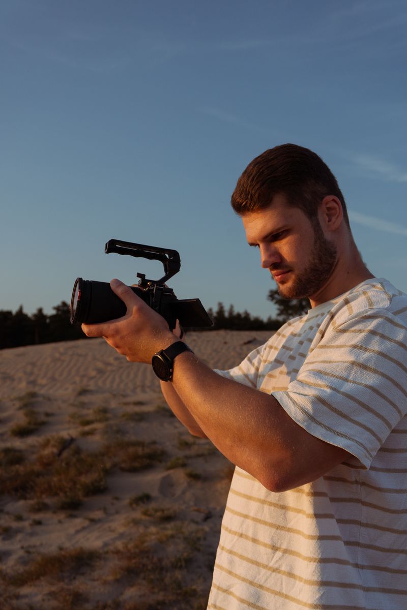 Persoon richt met zijn camera direct naar voren, staand in een open veld