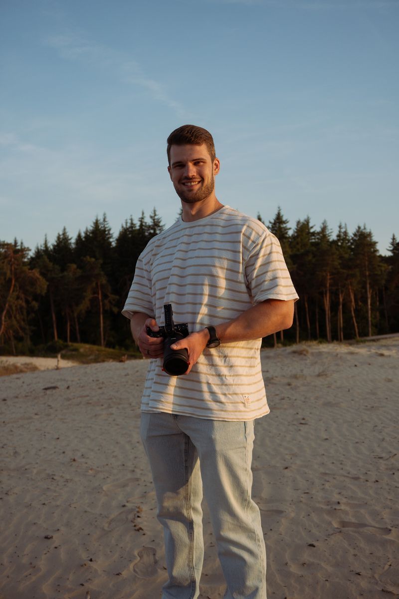 Persoon richt met zijn camera direct naar voren, staand in een open veld