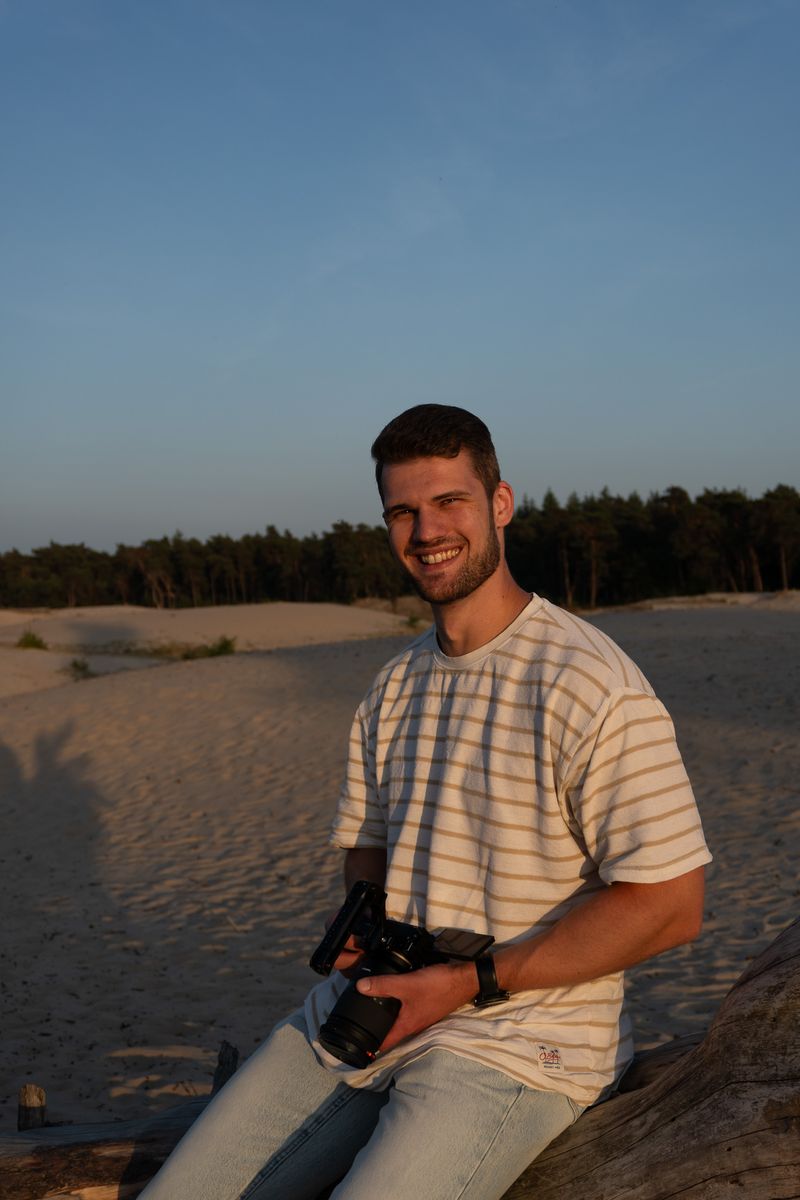 Persoon richt met zijn camera direct naar voren, staand in een open veld