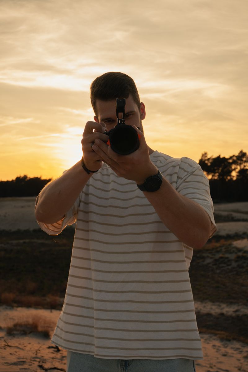 Persoon richt met zijn camera direct naar voren, staand in een open veld