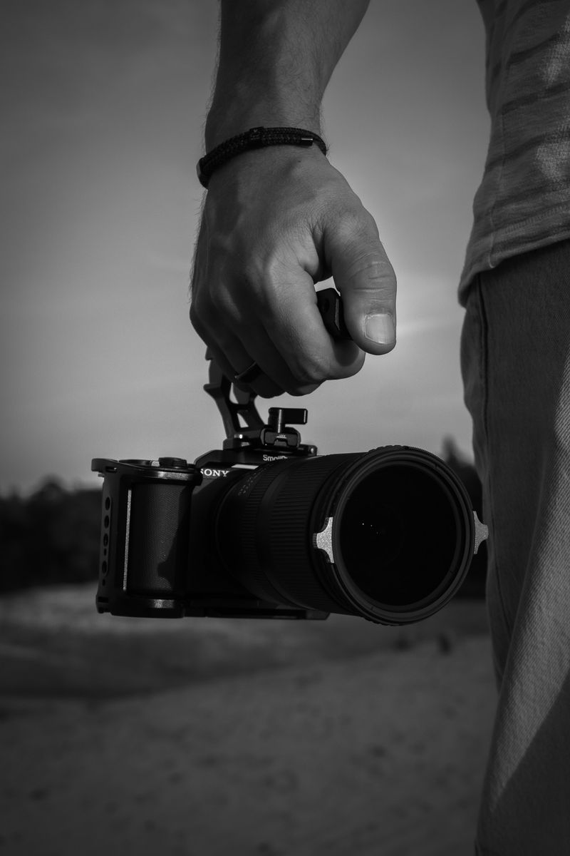 Persoon richt met zijn camera direct naar voren, staand in een open veld