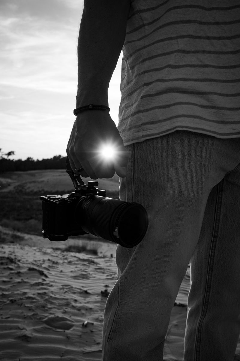 Persoon richt met zijn camera direct naar voren, staand in een open veld