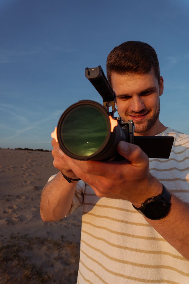 Persoon richt met zijn camera direct naar voren, staand in een open veld