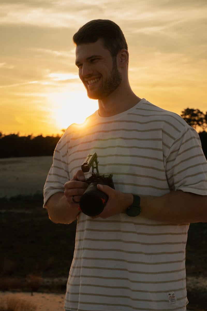 Persoon richt met zijn camera direct naar voren, staand in een open veld