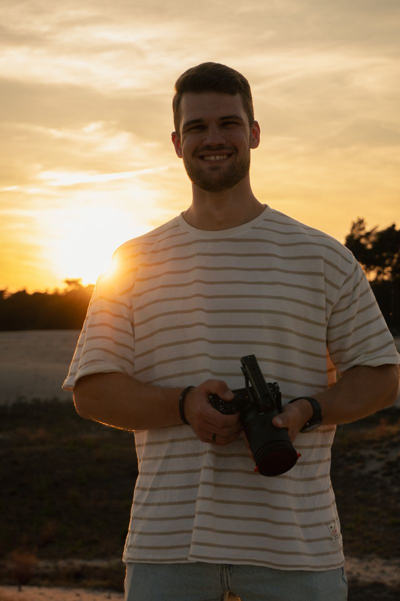 Persoon richt met zijn camera direct naar voren, staand in een open veld